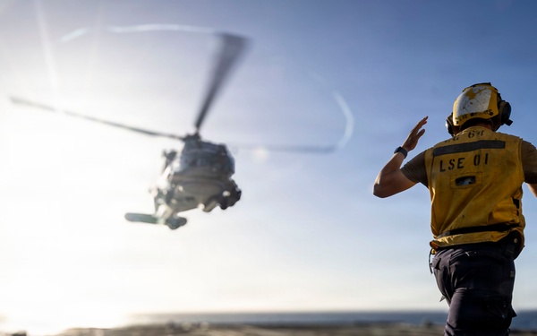 U.S. Sailor, assigned to the Iwo Jima Amphibious Ready Group, signals to an MH-60R Seahawk helicopter on the flight deck