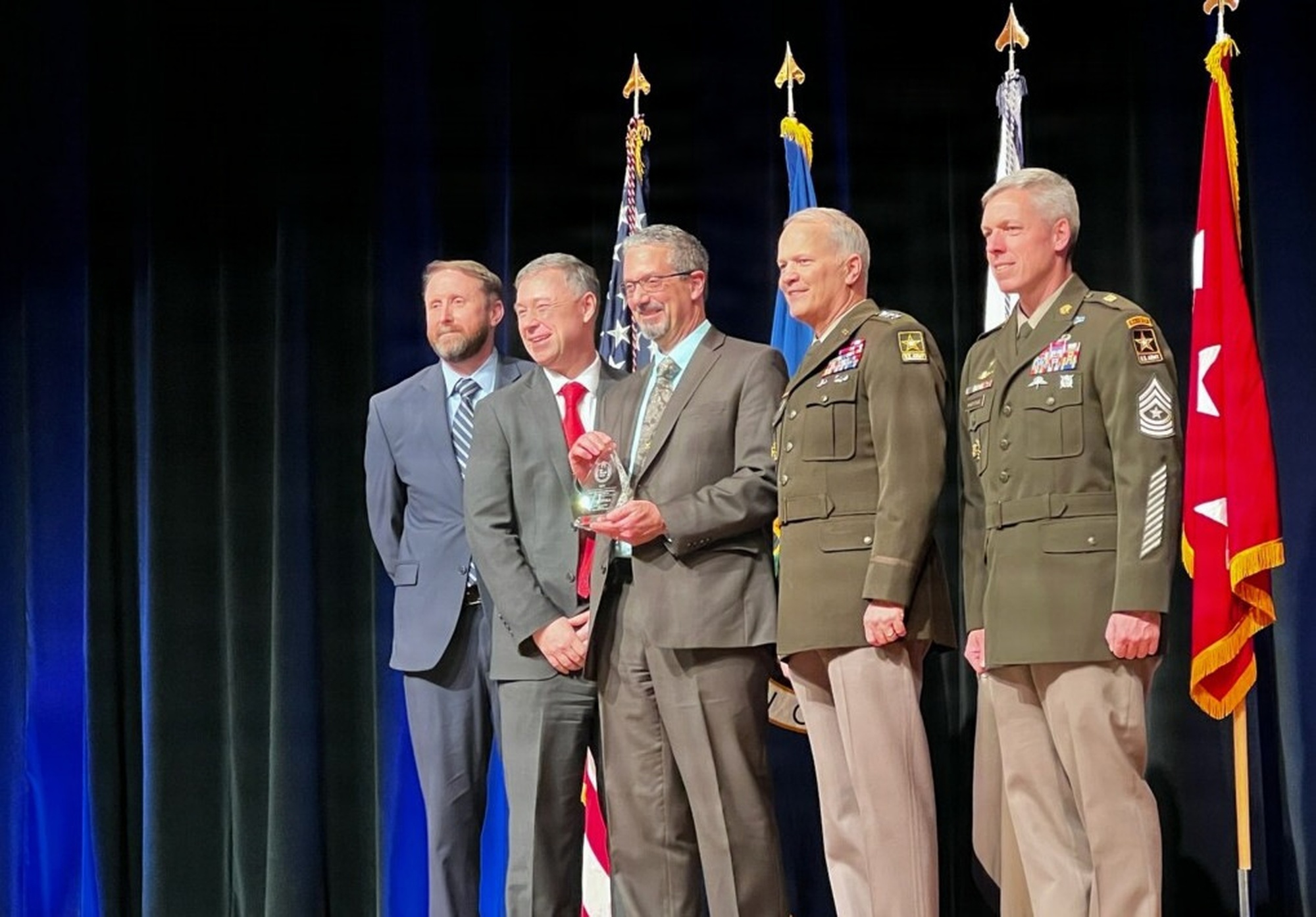 Marc Busala (center), receives the 2025 Army Acquisition Executive's Excellence in Leadership Engineering and Technical Management Professional of the Year Award during a ceremony on March 4 at the Pentagon. The Project Director Sensors-Aerial Intelligence Technical Director, Busala was recognized for building a highly complex and enterprise-wide data interoperability architecture which provides cross-domain solutions along with state-of-the-art sensor automation capabilities.