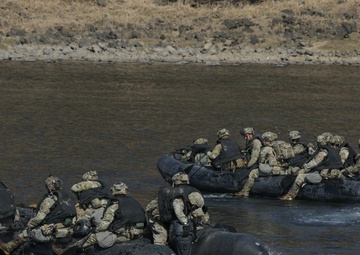Soldiers paddle Zodiac boats across the river