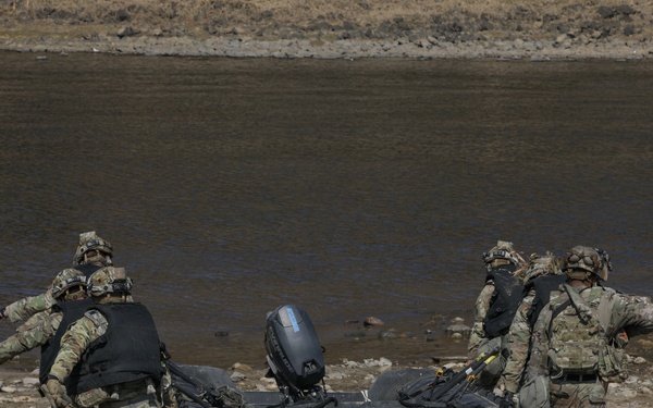Soldiers carry a Zodiac boat towards a river