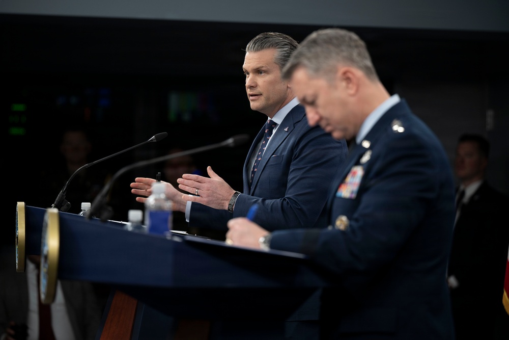 Secretary of War Pete Hegseth speaking at the Pentagon podium during a press briefing on Operation Epic Fury against Iran