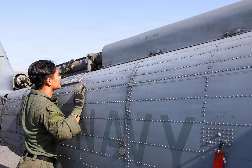 U.S. Sailors conduct preflight maintenance on an MH-60R Sea Hawk helicopter aboard USS John Finn