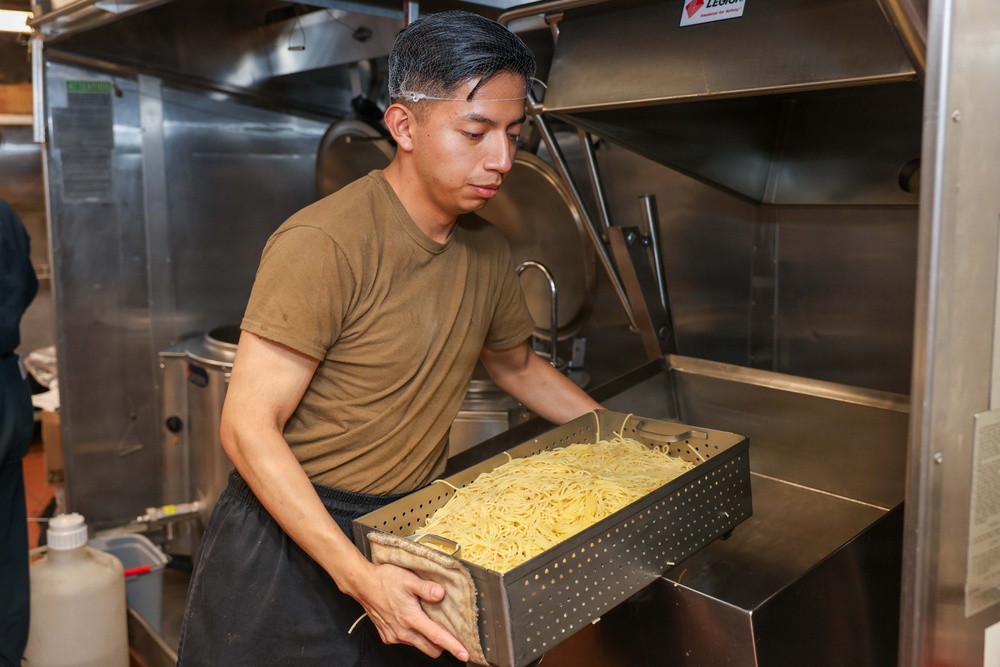 U.S. Sailors prepare food in the galley of USS John Finn