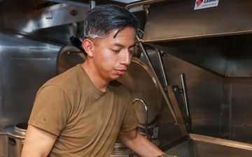 U.S. Sailors prepare food in the galley of USS John Finn