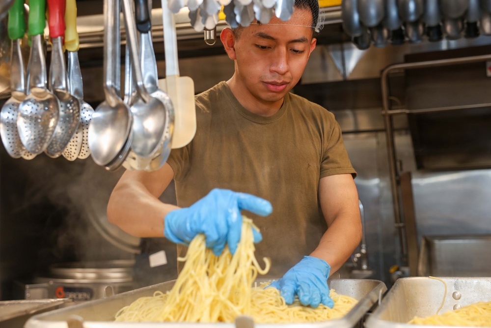 U.S. Sailors prepare food in the galley of USS John Finn