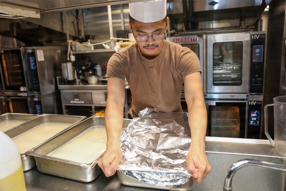 U.S. Sailors prepare food in the galley of USS John Finn