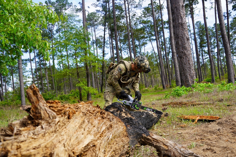 101st Soldier cuts wood to improve fighting position at JRTC