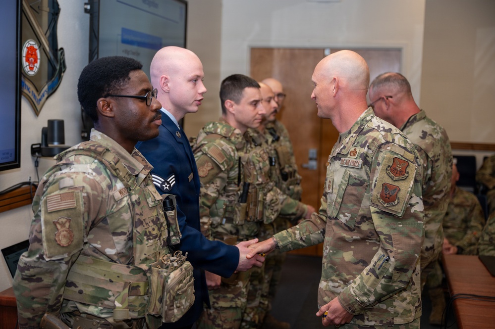 Chief Master Sgt. Andrew Rapsavage, 377th Air Base Wing command chief, presents a coin to Senior Airman Seth Fenton during a recognition ceremony at Kirtland Air Force Base