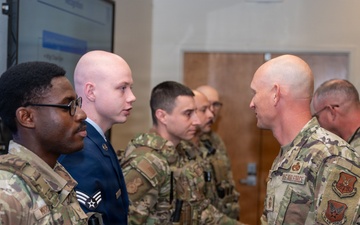 Chief Master Sgt. Andrew Rapsavage, 377th Air Base Wing command chief, presents a coin to Senior Airman Seth Fenton during a recognition ceremony at Kirtland Air Force Base