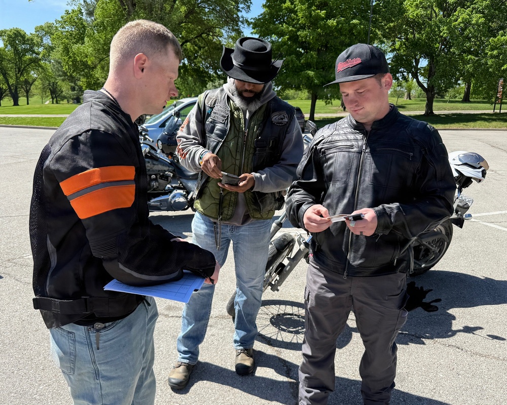 Motorcycle Safety Course Instructor Reviews Documentation with Riders at Outdoor Training Site