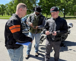 Motorcycle Safety Course Instructor Reviews Documentation with Riders at Outdoor Training Site