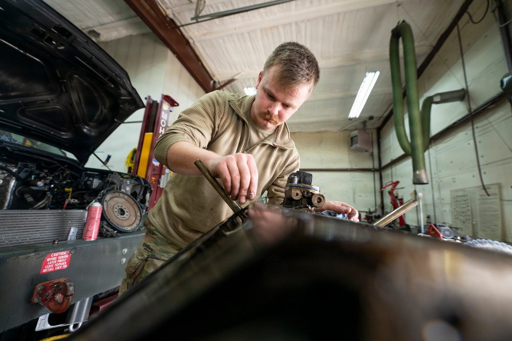 Vehicle maintenance specialist cleans engine gasket surfaces