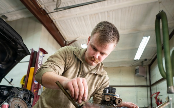 Vehicle maintenance specialist cleans engine gasket surfaces