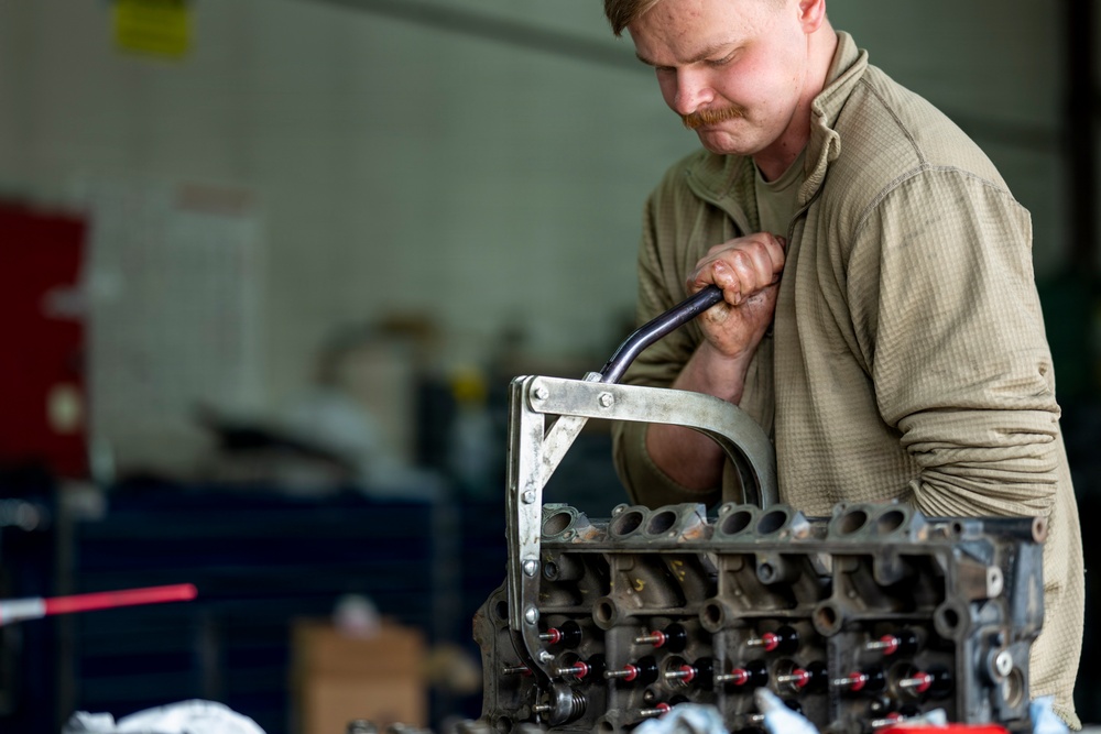 Vehicle Maintenance specialist compresses a spring for installation