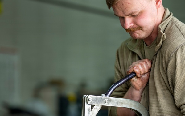 Vehicle Maintenance specialist compresses a spring for installation
