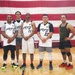 Army Reserve basketball team poses for group photo in front of American flag at Fort Knox gymnasium