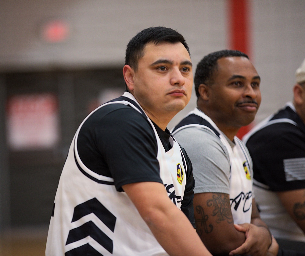 service members watch from the bench during an basketball game