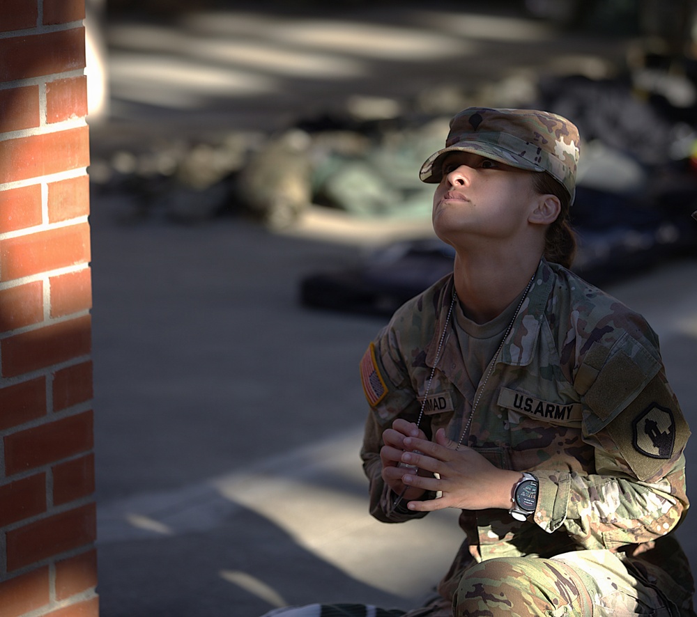 U.S. Army soldier pauses in quiet reflection near a brick structure during The Layout