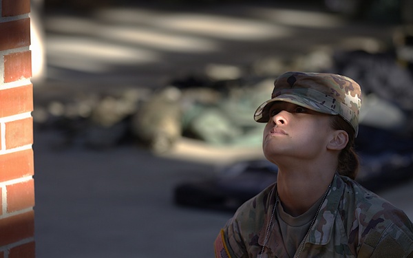 U.S. Army soldier pauses in quiet reflection near a brick structure during The Layout
