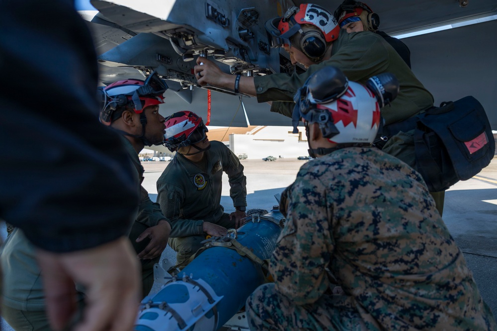 U.S. Marines and Sailors load ordnance on an F/A-18E Super Hornet