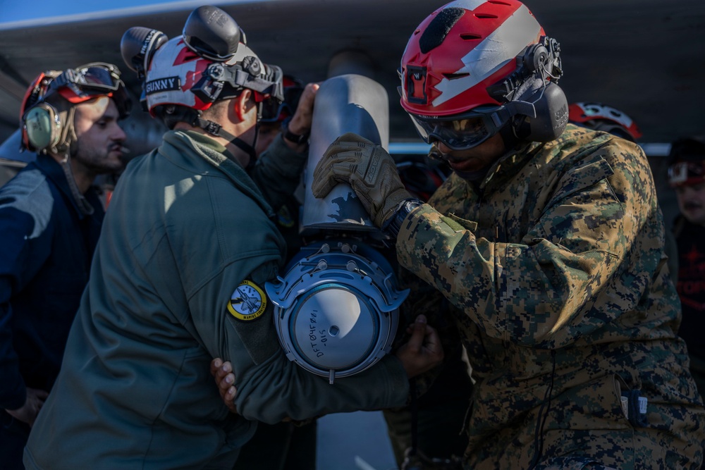 U.S. Marines and Sailors load ordnance onto an F/A-18E Super Hornet