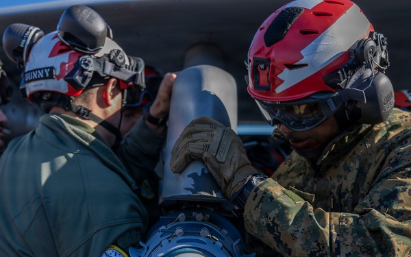 U.S. Marines and Sailors load ordnance onto an F/A-18E Super Hornet