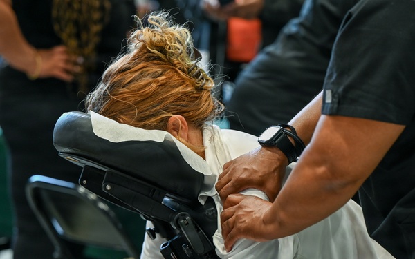 Massage therapist provides chair massage during military wellness event