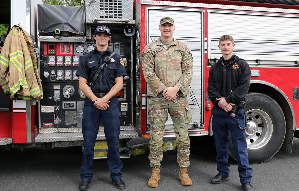 Army soldier meets with local firefighters in front of fire engine