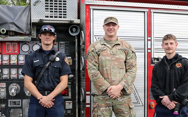 Army soldier meets with local firefighters in front of fire engine