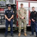 Army soldier meets with local firefighters in front of fire engine