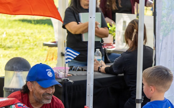 Volunteer Engages Child in Ring Toss Game at Military Family Community Event