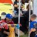 Volunteer Engages Child in Ring Toss Game at Military Family Community Event