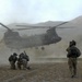 Soldiers brace themselves against the CH-47 Chinook helicopter rotor wash