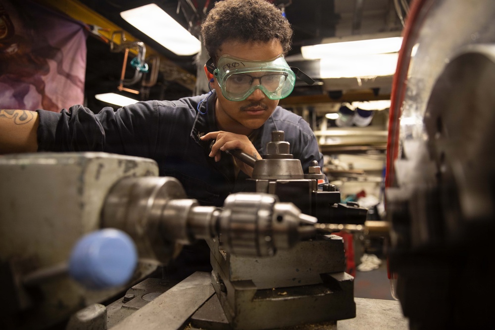 USS Mitscher (DDG 57) Sailor operates lathe in machine shop