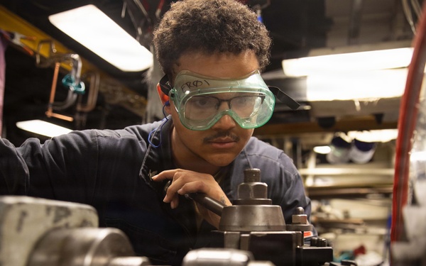 USS Mitscher (DDG 57) Sailor operates lathe in machine shop