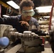 USS Mitscher (DDG 57) Sailor operates lathe in machine shop