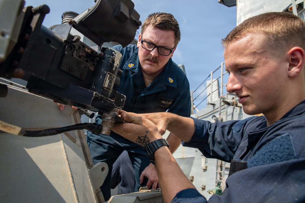 USS Mitscher (DDG 57) Sailors inspect 25mm machine gun