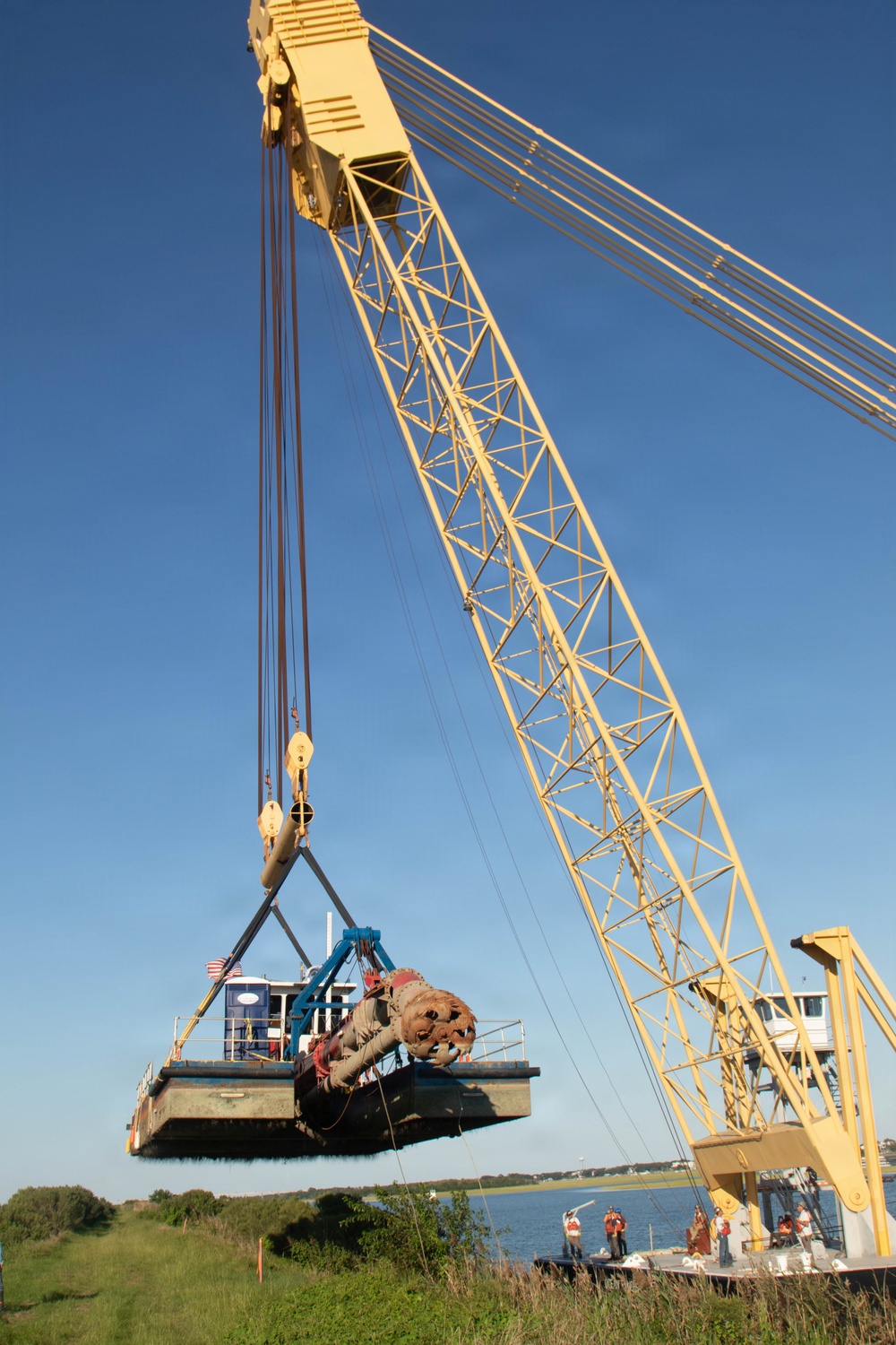 Large crane lifts dredge vessel during waterway construction or maintenance operation