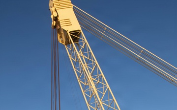 Large crane lifts dredge vessel during waterway construction or maintenance operation