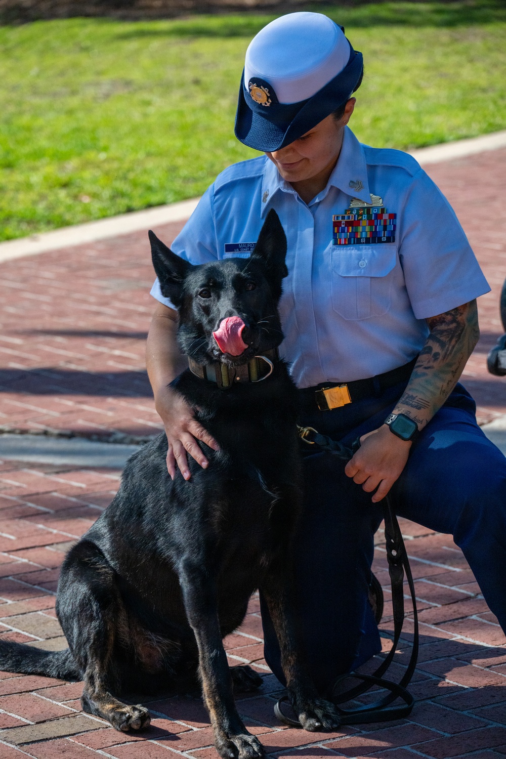 U.S. Coast Guard Service Member Poses with Military Working Dog During Ceremony