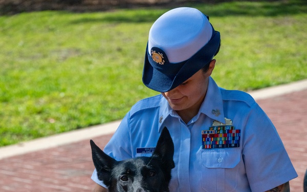 U.S. Coast Guard Service Member Poses with Military Working Dog During Ceremony