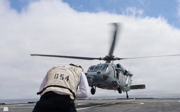 Aviation Boatswain's Mate Guides MH-60 Seahawk Helicopter Landing on Navy Ship Flight Deck