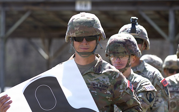 U.S. Army soldiers inspect paper targets during marksmanship qualification training at a firing range