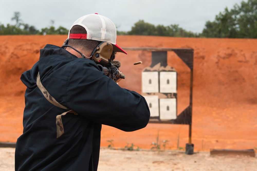 Shooter fires rifle at outdoor range as spent casing ejects during marksmanship training