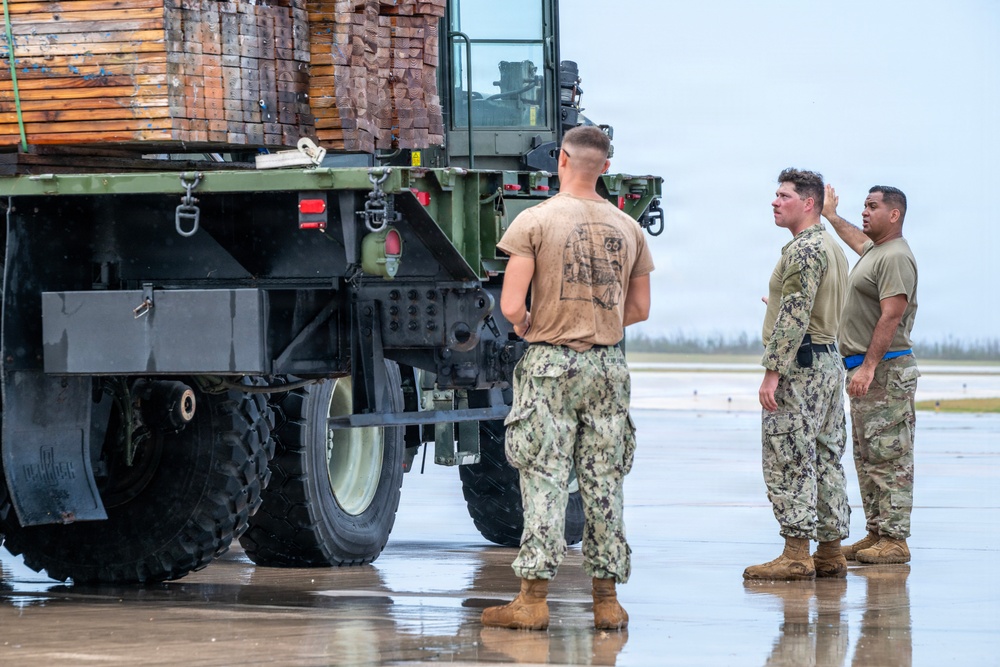 NMCB 1 Sailors and U.S. Airmen load wood cargo for roof restoration operations