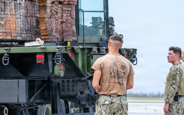 NMCB 1 Sailors and U.S. Airmen load wood cargo for roof restoration operations