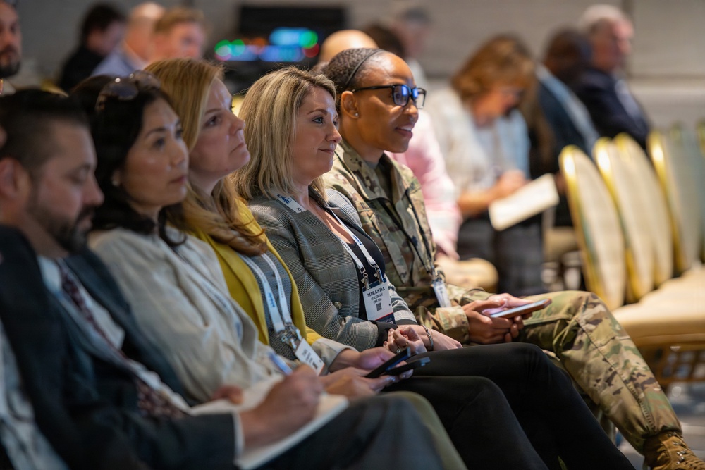 Military and civilian attendees listen to speakers at ABID