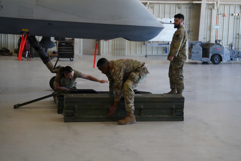 U.S. Air Force personnel conduct weapons loading operations on MQ-9 Reaper drone in hangar