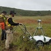 Technicians Operate Ground-Penetrating Radar Robot in Open Field During Unexploded Ordnance Survey