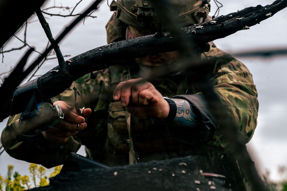 Soldier Prepares Munition Among Charred Trees in Forward Position